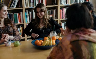 en gruppe personr som sitter ved et bord med en *** med frukt