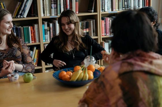 en gruppe personr som sitter ved et bord med en *** med frukt