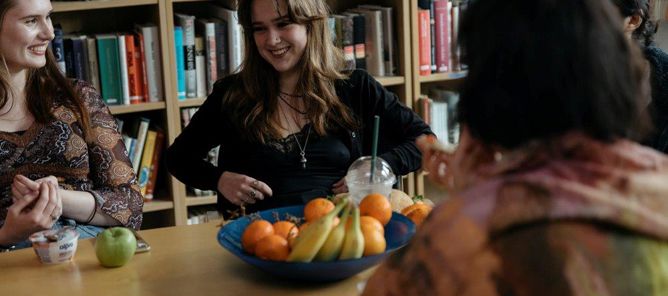 Foto: elever en gruppe personr som sitter ved et bord med en *** med frukt