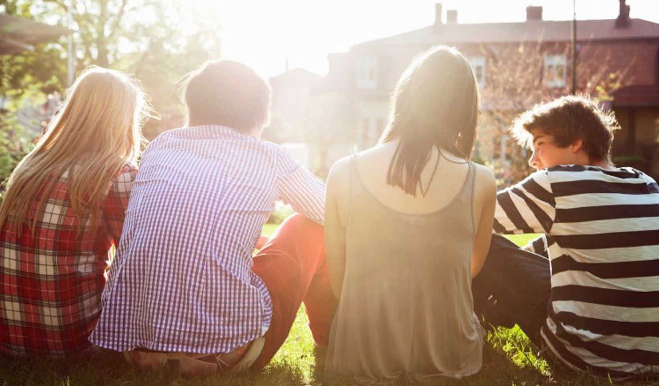Gjeng med ungdom sitter i solen.